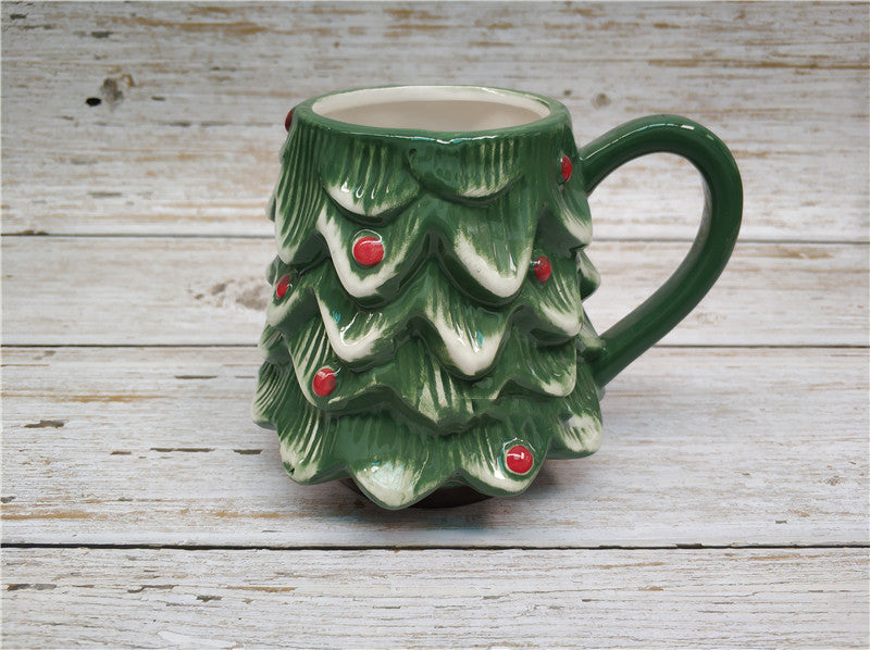 Mug shaped as the bottom half of a green Christmas tree with red ornaments on it and a C-shaped handle.