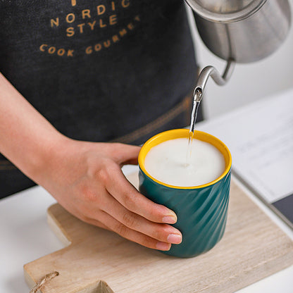 Person pouring water into a green&yellow Sweet Swirl mug.