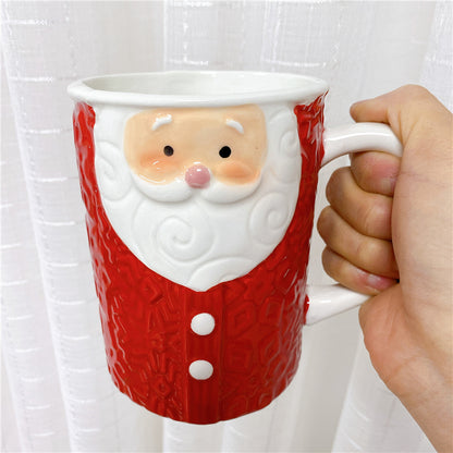 Hand holding a red and white Santa Clause shaped mug.