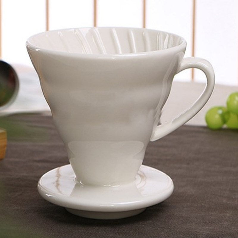 White Ceramic Pour Over Coffee Filter sitting on a table top covered in a dark gray table cloth.