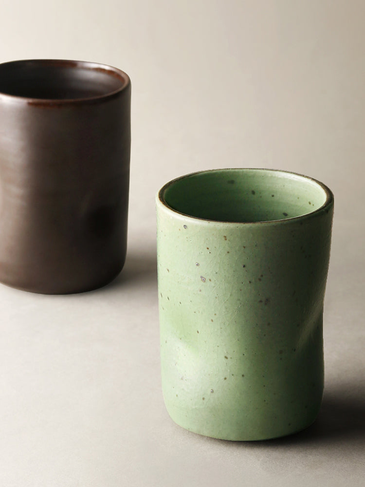 2 Misshapen Magic Japanese Style Tea Cup Mugs in matcha green and mocha brown colors.