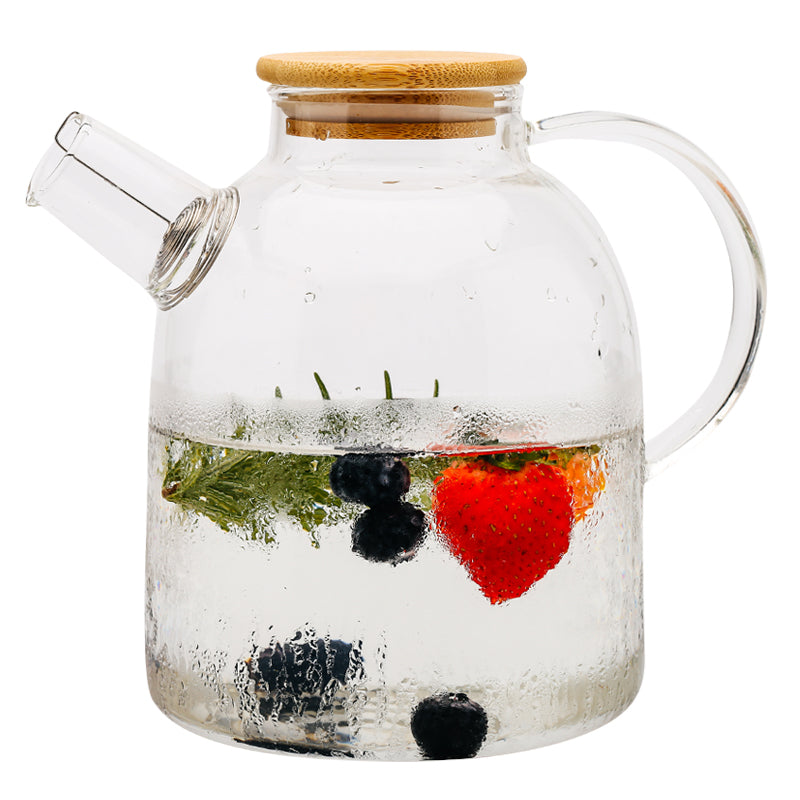 Clear Glass Cold Kettle With Bamboo LidClear Glass Pitcher With Bamboo Lid with water and fresh fruits inside of it.