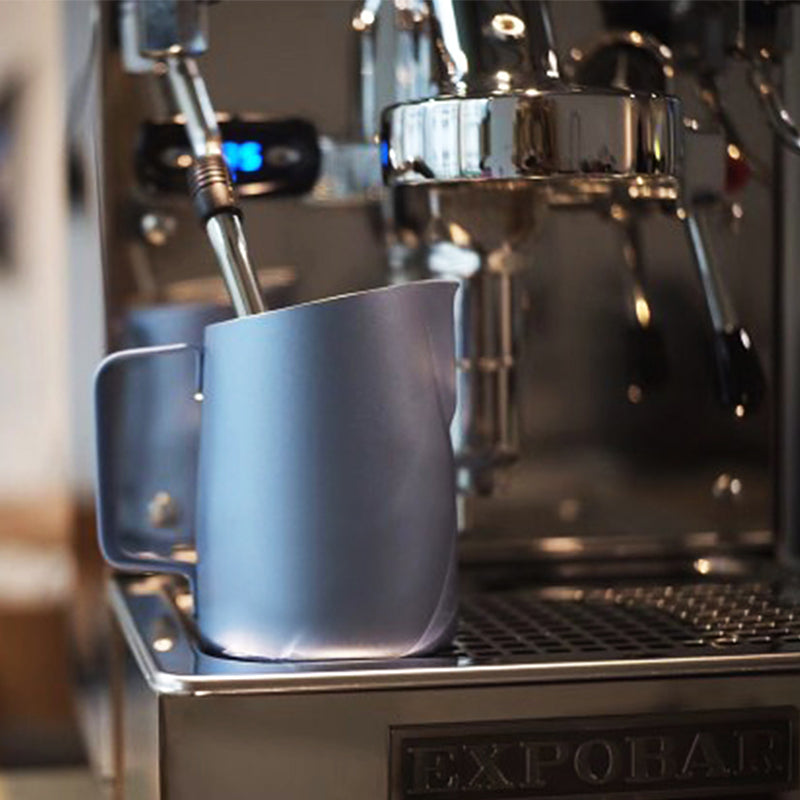 Stylish Barista Milk Pitcher with Cool Skull Design by Espresso Parts, with a milk steamer in it, on an espresso machine.