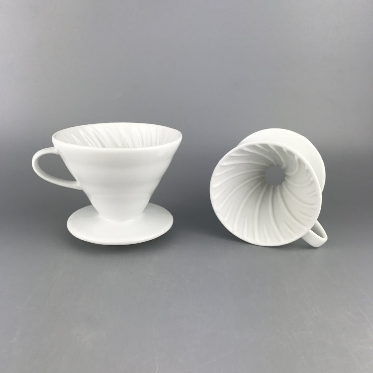 2 white Ceramic Pour Over Coffee Filters on a gray backdrop. The ceramic coffee filter on the left is upright and the ceramic coffee filter on the right is on its side with the top side facing forward so the swirl pattern on the inside of the coffee filter is displayed.