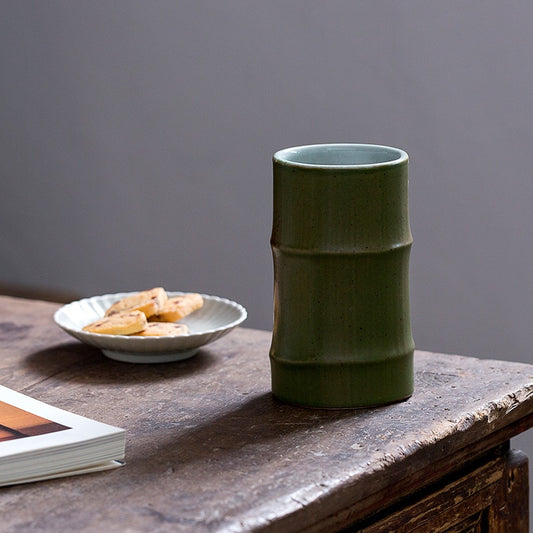 Medium Handmade Ceramic Bamboo Shoot Shaped Cup  on table with plate that has biscuits on it. There is also a book on the table.