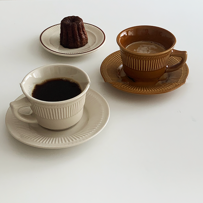 2 coffee cup and saucer sets . One is in Cappuccino Brown color and the other is in French Vanilla color. There is another plate with bread pudding on it.