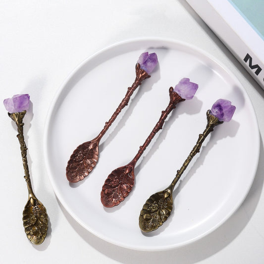 Natural Amethyst Crystal Spoons. 3 of them are on a white plate on a table, and the other one is on the table.