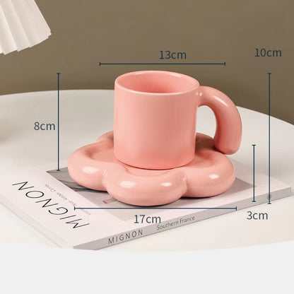 Fun and Bubbly Mug and Saucer Set in pink on top of a book, on top on a table. There is a lamp shade on the top left of the photo. There are product dimensions shown on the photograph.