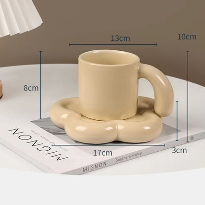 Fun and Bubbly Mug and Saucer Set in beige on top of a book, on top on a table. There is a lamp shade on the top left of the photo. There are product dimensions shown on the photograph.